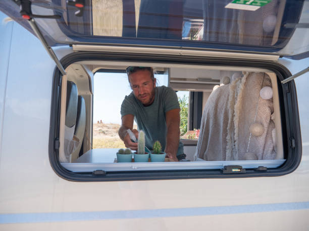 istock Man looks after plants and cactuses in his camper van 1392545375