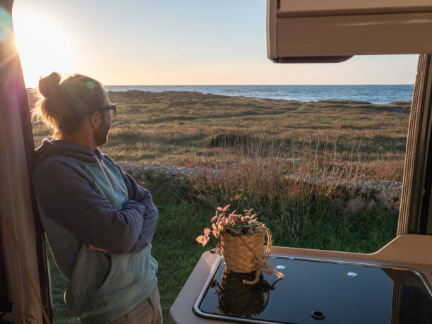istock Man lying in a van looking at ocean 1392545634