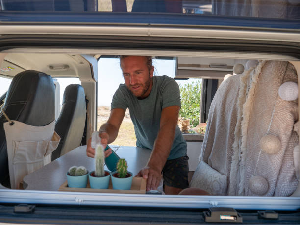 istock Man looks after plants and cactuses in his camper van 1392545666