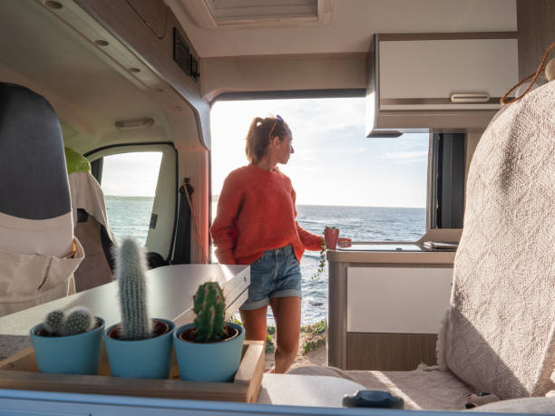 istock Woman in her van looking at ocean 1392545915