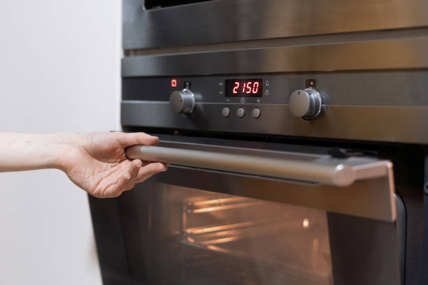 istock Person's hand opening black oven in kitchen 1392545923