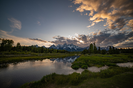 Sunset view across the Snake River at the Teton Peaks in Grand Teton National Park near Jackson Hole, Wyoming within the United States of America {USA).