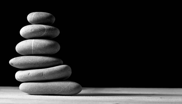 stack of six smooth gray stones in balance over black background