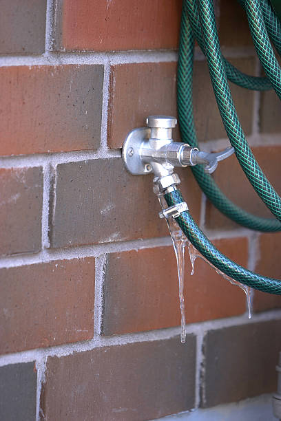 An exterior leaking water tap connected to a hose on bricks Frozen hose. 2004 2004 stock pictures, royalty-free photos & images