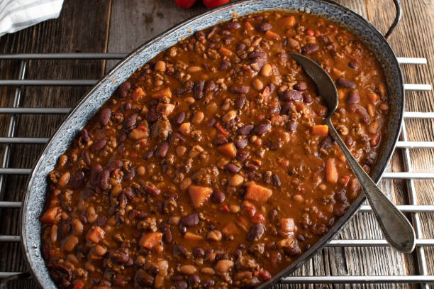 Chili con carne with sweet potatoes Delicious homemade cooked bean stew alla chili con carne with ground beef and sweet potatoes. Served in a rustic skillet on wooden table, Overhead view baked beans stock pictures, royalty-free photos & images