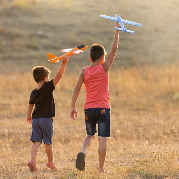 2人の男の子がおもちゃの飛行機、夏のコンセプトを立ち上げる屋外で遊ぶ - group of people people family multi ethnic group ストックフォトと画像