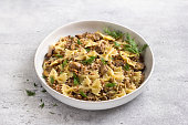 Traditional Jewish dish kasha varnishkes: buckwheat, pasta, champignon mushrooms, fried onions with herbs on a gray textured background, vegan food