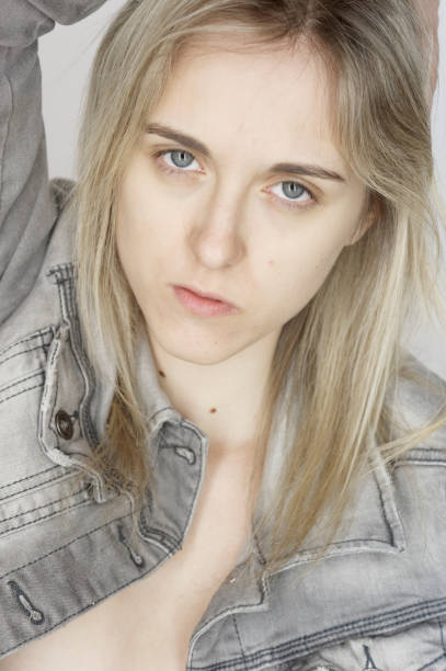 Portrait of young blond girl Portrait of young blond girl with jeans jacket standing and sitting on wicker armchair costantino stock pictures, royalty-free photos & images