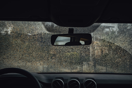 Blurred rain drops on a car window with the mirror in the background. Close up