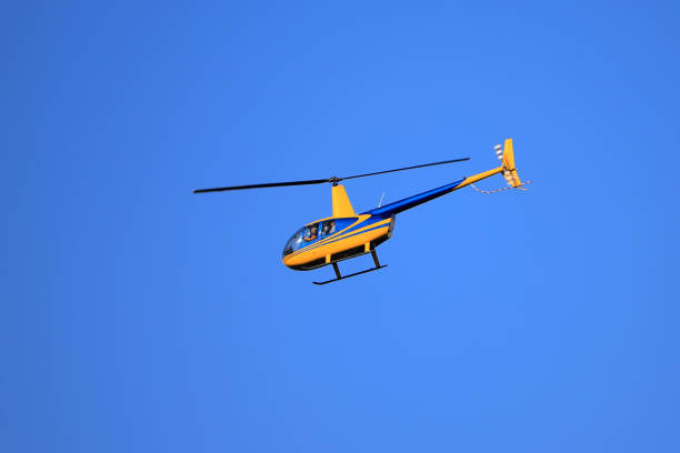 The helicopter Robinson R44 flies in the blue sky