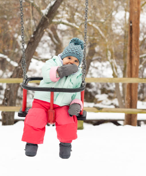 menina balançando em um dia de neve. - playground snow winter little girls - fotografias e filmes do acervo