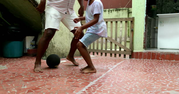 African father and son playing football. Parent and child bonding, Black dad and kid active sport stock photo