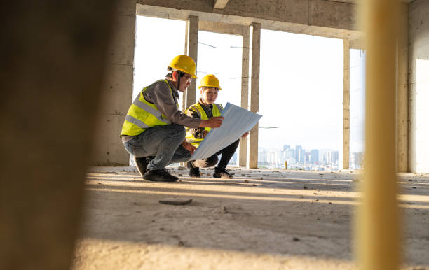 istock Male and female engineers looking at blueprints at construction site 1392568300