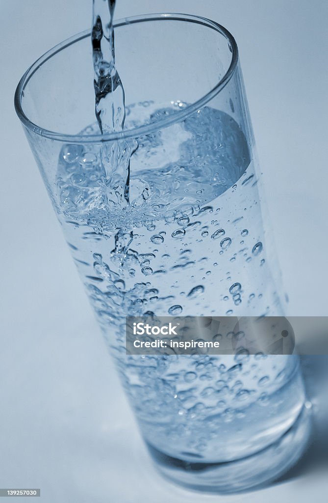 Water being poured water beign poured into a glass. Blue tones. Focus on the middle of the glass. Bubble Stock Photo