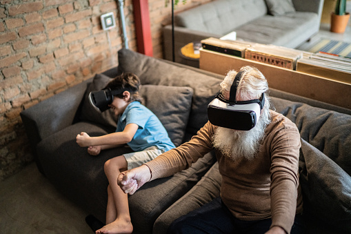 Grandfather and grandson playing with VR glasses at home