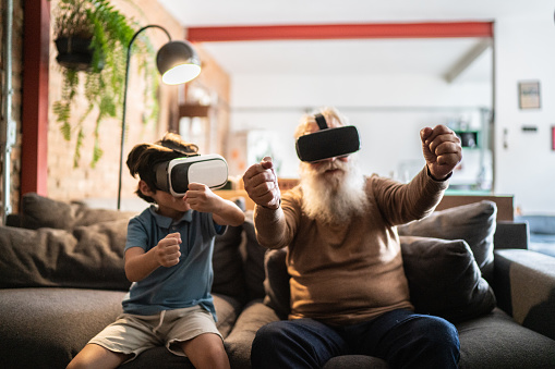 Grandfather and grandson playing with VR glasses at home