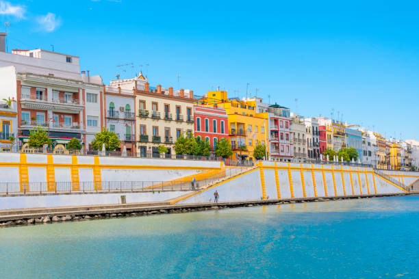 die leuchtenden farben des viertels triana entlang des flusses guadalquivir in der historischen andalusischen stadt sevilla, spanien. - seville water spain european culture stock-fotos und bilder