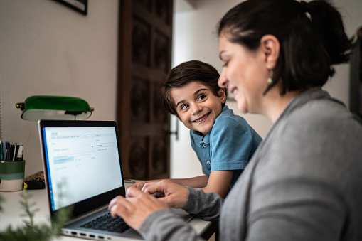 Mature woman using laptop and talking to son at home