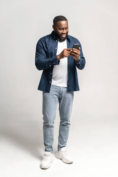 istock Joyful and carefree African-American man using smartphone isolated on grey 1392577292
