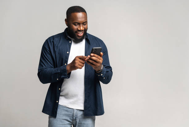 istock Black guy chatting online, using new mobile app, full length 1392577317