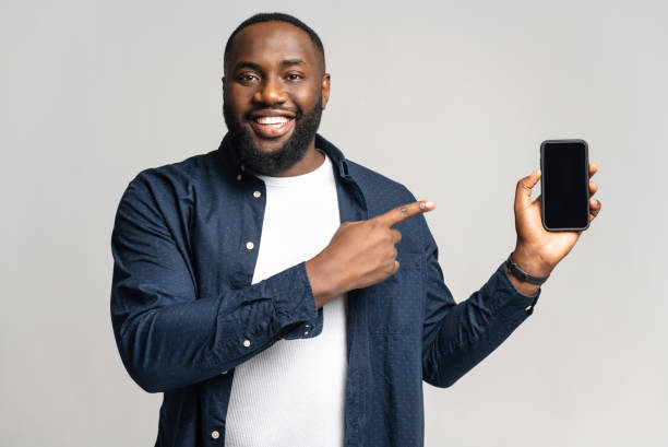 istock Excited Africal man with smartphone in the hand isolated on gray background 1392577544