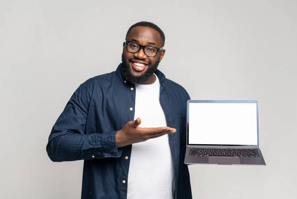 istock Black guy points with palm at blank screen, advertising new app 1392578942