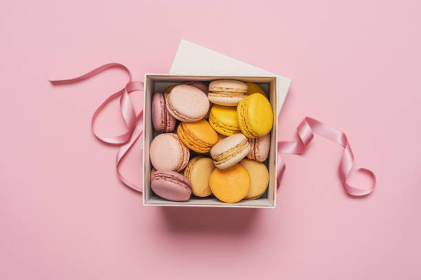 ピンクのパステルカラーの背景にギフトボックスにマカロンアーモンドビスケット - お菓子 ストックフォトと画像