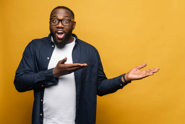 istock Amazed African American man pointing with palms on the blank space for advertisement 1392579072