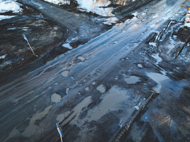 Broken old asphalt road outside the city. Pits and potholes. Aerial view stock photo