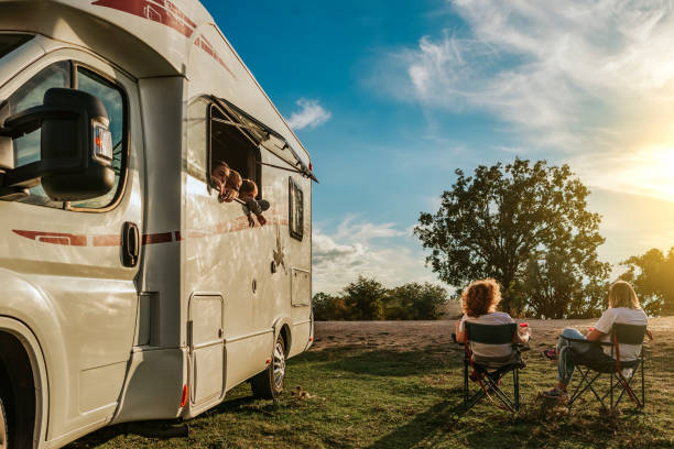 dzieci wychylające się przez okno karawany, obserwujące swoje matki pijące kawę. koncepcja rodziny w przyczepie kempingowej - motorhome zdjęcia i obrazy z banku zdjęć