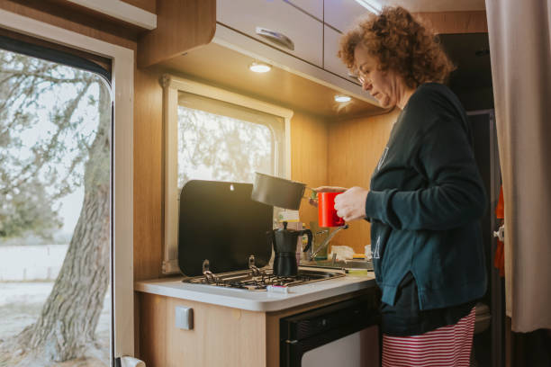 A woman prepares coffee in the kitchen of a caravan. stock photo