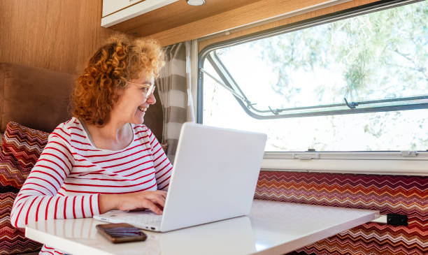 A woman works with a laptop computer inside a caravan. stock photo