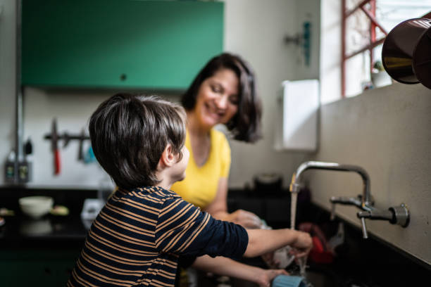 istock Boy washing dishes with mother at home 1392582223