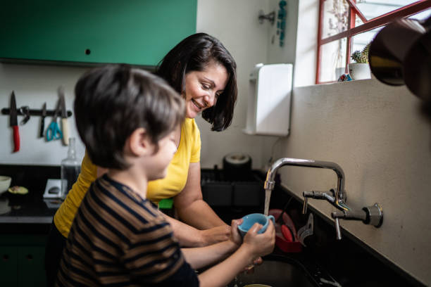 istock Boy washing dishes with mother at home 1392582235