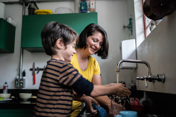 istock Boy washing dishes with mother at home 1392582246