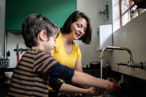 istock Boy washing dishes with mother at home 1392582273