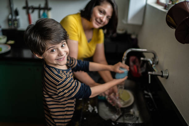 istock Boy washing dishes with mother at home 1392582299
