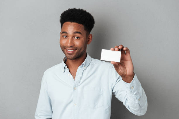 istock Smiling young afro american guy holding blank business card 1392582896