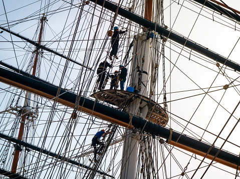 A group of four people, plus an instructor, who are climbing the rigging on the Cutty Sark sailing ship in Greenwich, London.