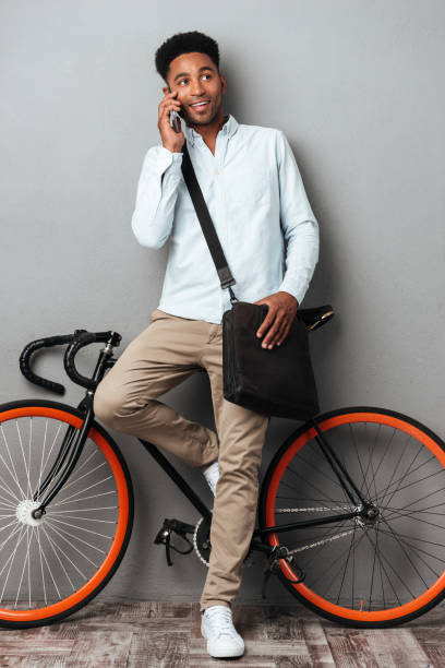 istock Handsome man standing near bicycle talking by phone. 1392584402