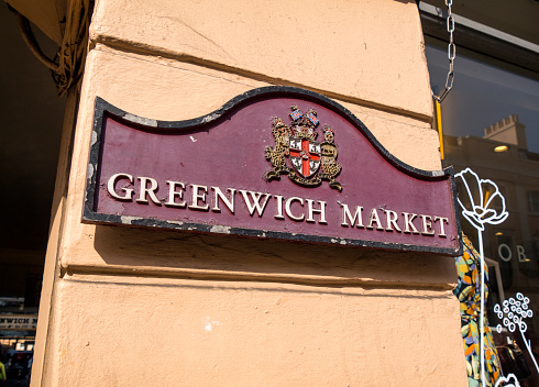 An old-fashioned and rather dilapidated sign on a wall outside Greenwich Market in South East London.