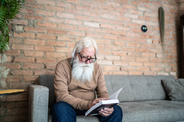 istock Senior man reading a book at home 1392586215
