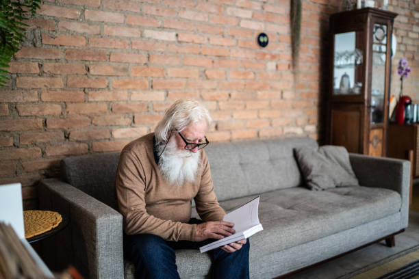 istock Senior man reading a book at home 1392586246