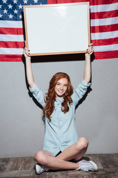 istock Happy redhead young lady holding copyspace board 1392587365