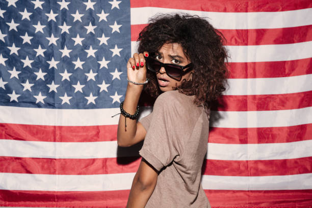 istock Serious african young lady standing over USA flag 1392587707