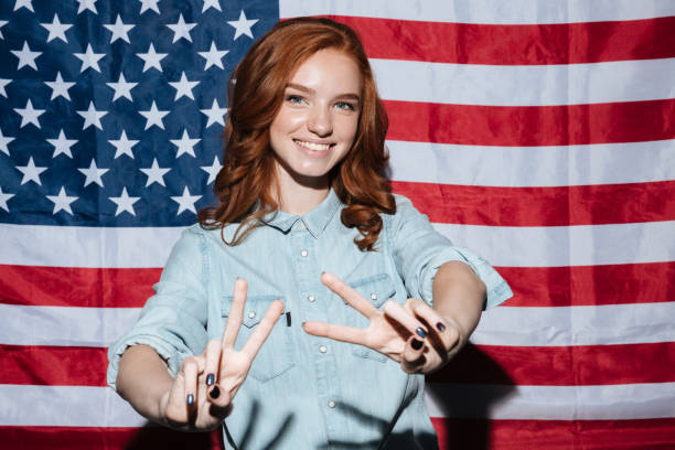 istock Cheerful redhead young lady showing peace gesture. 1392587918