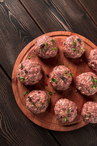 istock Raw meatballs, with micro greenery, on a cutting board, homemade, rustic, no people, 1392587975
