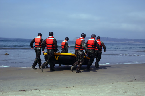 a group of U.S. Navy SEALS  in training.  They carry the boat out to shallow water, get in and row out about a quarter mile.  Then they wait for the command to row back in to shore, land on rocks and have to carry the boat over their heads across the rocks.  Quite an interesting exercise to witness.  note that they are in full gear with boots and all.  
