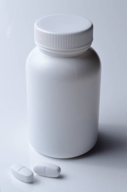 istock white plastic medicine jar and two white pills. light background. 1392592219