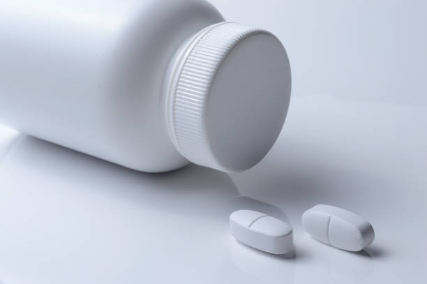 istock white plastic medicine jar and two white pills. light background. 1392592221